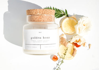Golden Hour 100% soy wax candle with cork lid, styled with fresh lemon slices, ginger root, and flowers. Hand-poured, eco-friendly candle featuring a blend of amber, lemon, ginger, patchouli, and wood for a non-toxic, clean fragrance.